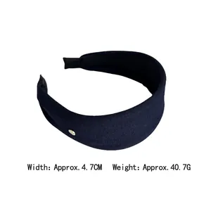 Minimalist wide fabric headband in deep blue knit texture with golden button detail