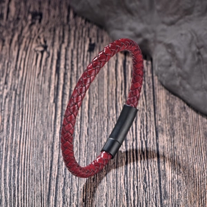 Detail von rotem geflochtenem Lederband und mattem schwarzem Metallverschluss auf Holz