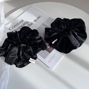 Detail of two black velvet scrunchies with silver glitter and handmade woven labels