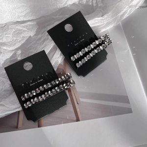 Close-up of four sparkling crystal hair pins with black metal base on a display card