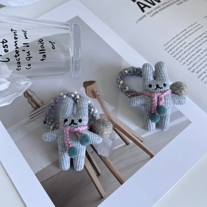 Détail de chouchous lapin en tricot gris avec écharpes roses sur une table blanche