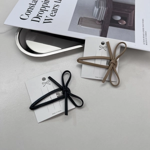Detail shot of black and brown faux leather bow hair clips on a white display card