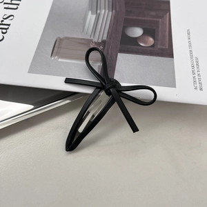 Detail of a chic black leather bow hair clip on a silver metal alligator clasp fastener