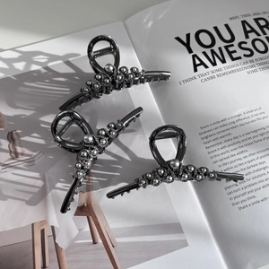 Elegant gunmetal alloy hair claws with grey pearls on magazine background