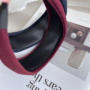 Detail showing the burgundy knit fabric and black satin lining of the wide padded headband