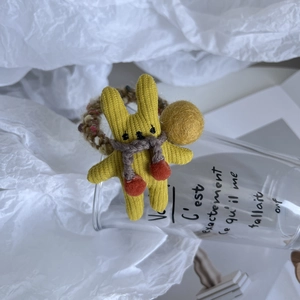 Détail d'un chouchou lapin en tricot jaune avec un élastique tissé multicolore