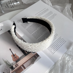 Close-up of white tweed padded headband with sequin texture on a fashion magazine