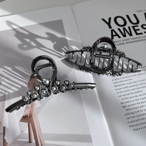 Elegant gunmetal claw clips set with pearls and rhinestones on a stylish magazine background
