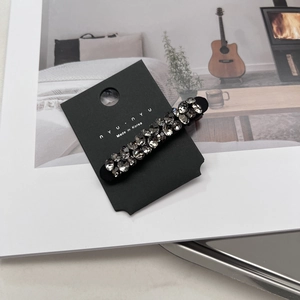 Détail d'une pince à cheveux de luxe avec cristaux gris foncé sur carte de support