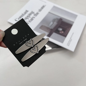 Détail de barrettes à cheveux coeur en strass argentés sur carte de marque
