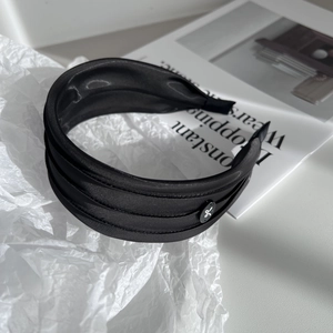 Detail of the triple-layered black satin headband with a small white bow logo accent