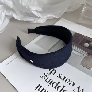 Detail of dark blue fabric headband with fine knit texture and small gold metal accent button