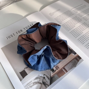 Detail eines großen Denim-Haargummis mit zweifarbigem blau-braunem Stoff und Faltenoptik