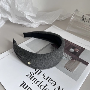Detail of dark grey fabric wide headband with golden button on fashion magazine