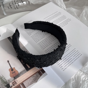 Detail of black tweed headband with sequins on a magazine background for elegant style