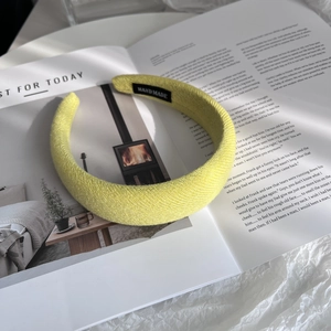 Detailed close-up of a bright yellow knitted headband with handmade label on magazine