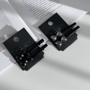 Set of four elegant bow hair clips with crystal accents on a black display card