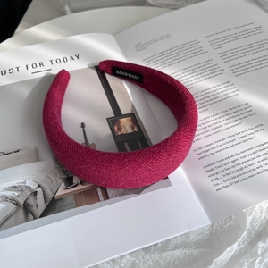 Detailed macro view of berry red knitted headband with handmade label on magazine