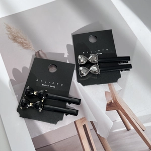Elegant black bow hair clip set with sparkling crystal heart details on packaging