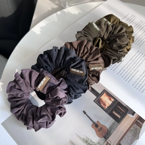 Détail de quatre chouchous en tissu violet, noir, marron et vert sur un magazine