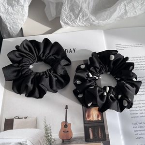 Detail of high-quality black satin and white polka dot scrunchies on a magazine