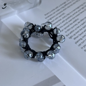 Macro des perles de cristal gris-bleu sur un élastique à cheveux noir tressé robuste