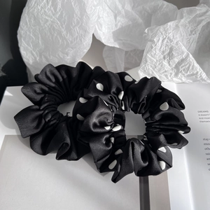 Set of two satin scrunchies in solid black and polka dot patterns on paper background
