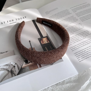 Detail of dark brown wool knit headband featuring a handmade woven label and thick texture