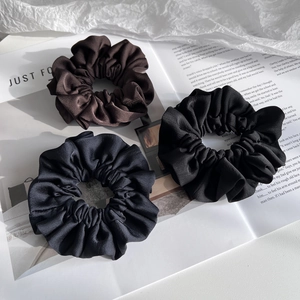 Three-piece set of satin silk scrunchies in black, brown, and navy blue on a magazine page