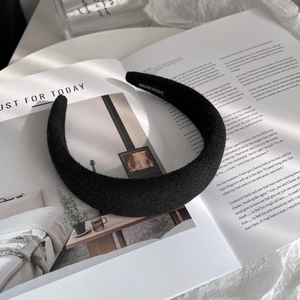 Detailed close-up of handmade wide black wool hairband on a fashion magazine