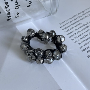 Détail de perles de cristal facettées sur un élastique noir aux reflets brillants