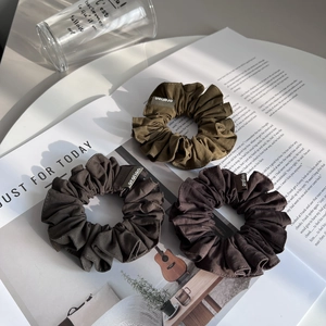 Trois chouchous minimalistes en tissu olive, gris et marron sur un magazine