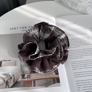 Detail of a brown plaid scrunchie with vintage eyelet lace trim on a lifestyle magazine