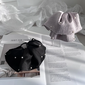 Elegant fabric bow hair clips with pearls in black and lavender on a magazine background