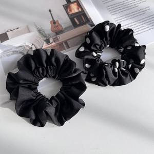 Classic black satin and white polka dot hair scrunchies set on white wood background