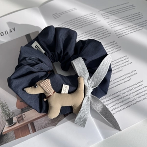 Détail de chouchou bleu marine avec peluche de teckel marron et petit grelot métallique