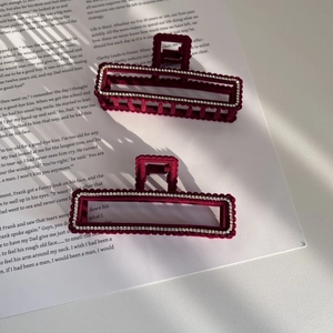 Set of two elegant burgundy flocked claw clips with rhinestones on a magazine background