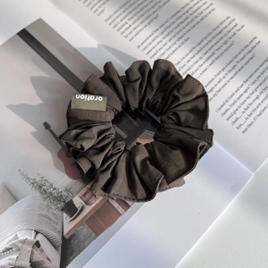 Vue détaillée d'un chouchou en tissu plissé marron foncé sur un magazine ouvert