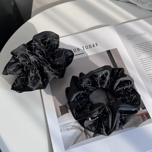 Vue détaillée de chouchous en satin noir avec motifs d'étoiles en strass brillants