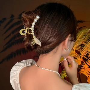 Pince à cheveux queue de poisson dorée avec perles et strass portée par un mannequin