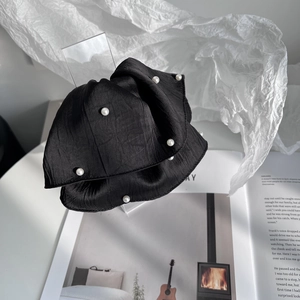 Detailed view of the black fabric hair claw with white pearls on an open magazine