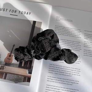 Gros plan d'un chouchou en satin noir avec motifs de feuilles en strass brillants