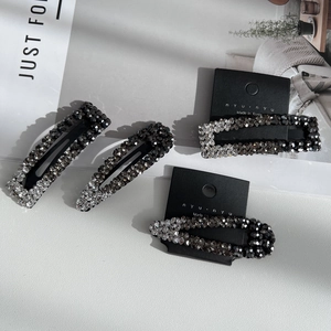 Detailed close-up of four luxury BB hair clips with sparkling grey and black rhinestones