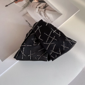 Detail of black satin hair claw clip with silver rhinestone cross pattern on a white desk