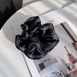 Elegante elastico scrunchie in raso nero con bordo di perle su una rivista trendy