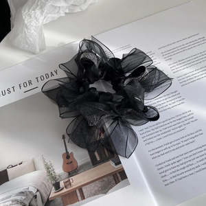 Elegant black organza scrunchie with silver rhinestones on a magazine background