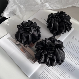 Three elegant black fabric cloud hair clips with silver beaded edges on magazine background