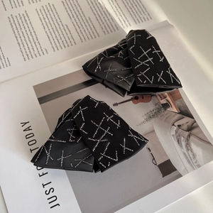 Elegant black satin hair clips with crisscross silver rhinestones on an open magazine