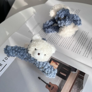 Cute blue plush hair claw clip with a 3D white teddy bear design on a magazine background