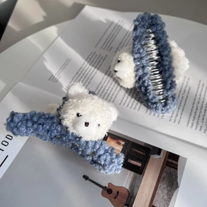 Cute blue knit hair claw clip with white plush bear on a magazine background